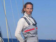 Paola, dressed in sailing outfit, on her sailing boat, is smiling